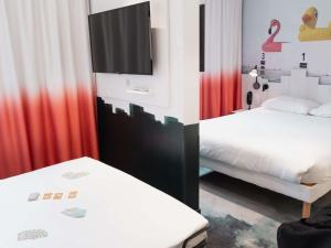 a bedroom with two beds with red curtains and a tv at ibis Styles Thonon-les-Bains in Thonon-les-Bains +57 photos