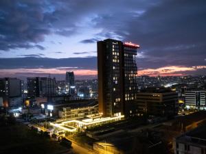 a city lit up at night with a tall building at Movenpick Living Istanbul West in Istanbul