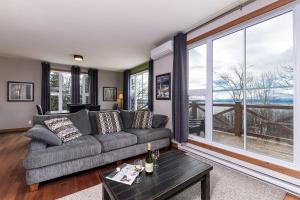 a living room with a couch and a table at Condo 120B, Hot Tub, Panoramic Views & Game Area in Petite-Rivière-Saint-François