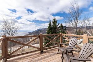 two chairs on a wooden deck with a view at Condo 120B, Hot Tub, Panoramic Views & Game Area in Petite-Rivière-Saint-François