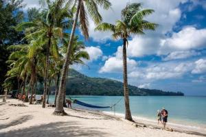 a couple walking on the beach with palm trees at kamala beachside escape in Kamala Beach