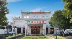 a white building with a sign on the front of it at Vienna Hotel Shanghai Hongqiao Hub National Exhibition Center Huqingping Road in Shanghai
