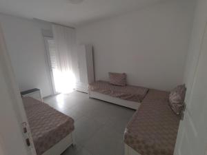 Una pequeña habitación con dos camas y una ventana. en Appartement F3 Oran, en Bir el Djir