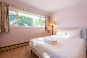 a bedroom with a white bed with a window at South Vancouver Garden Home in Vancouver