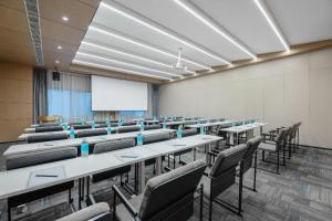 Una sala de conferencias con mesas, sillas y una pizarra. en Atour X Hotel Jinan Jingshi Road Provincial Sports Center, en Jinan