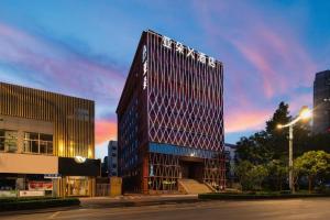 Un edificio alto con un cartel al costado. en Atour X Hotel Jinan Jingshi Road Provincial Sports Center, en Jinan