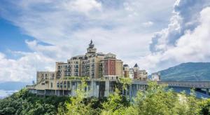 a large building on top of a hill next to a bridge at eLong Hotel (HUA Shenzhen Bay Branch) in Shenzhen
