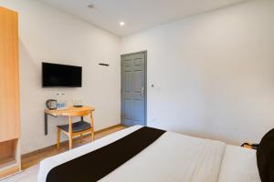 Un dormitorio con una cama, un escritorio y un televisor. en Townhouse Sarjapur Road Formerly Hotel Ace, en Bangalore