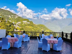 a group of tables and chairs on a balcony with mountains at Staynest Continetal With parking Near Mg Marg in Gangtok