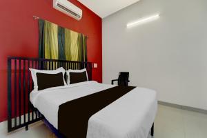 a bedroom with a bed with a red wall at Super Hotel O Auroville Bird Sanctuary Chennai Formerly Vanam Resort in Puducherry