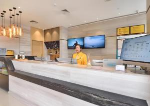una donna in piedi al bancone di un ristorante di City Comfort Inn Wuhan Hankou Bei Light Rail Station a Wuhan