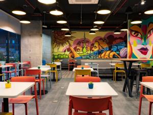 a restaurant with tables and chairs and a mural at ibis budget Bogota Marly in Bogotá