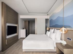 a bedroom with a large white bed and a tv at Novotel Chandigarh Tribune Chowk in Chandīgarh +58 photos