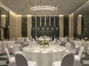 a conference room with white tables and chairs and a chandelier at Hyde Hotel Dubai in Dubai +101 photos