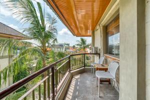 einen Balkon mit einem Tisch, Stühlen und einer Palme in der Unterkunft Sejuk Suites in Legian