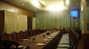 a long table in a room with chairs and a television at Thai Hotel Krabi in Krabi town