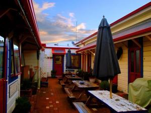 eine Terrasse mit Tischen und einem Sonnenschirm auf einem Gebäude in der Unterkunft Stables Lodge Backpackers in Napier
