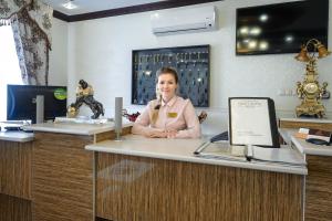 una mujer sentada en un escritorio en una oficina en Hotel Gold, en Volgograd