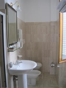 W łazience znajduje się umywalka, toaleta i lustro. w obiekcie Hotel Gioia Garden w mieście Fiuggi