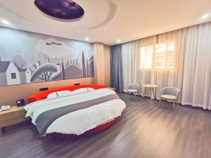 a bedroom with a large bed with a painting on the wall at Thank Inn Plus Hotel Jiangyin University in Wuxi