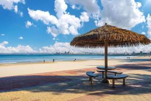 a beach with a straw umbrella and two benches at Pohang Hotel View in Pohang