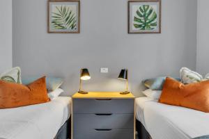 two beds in a room with two lamps on a nightstand at The Palms Apartments in Merimbula