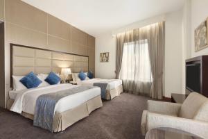 una habitación de hotel con dos camas y un sofá en Howard Johnson Bur Dubai, en Dubái 50 fotos más