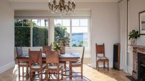 a dining room with a table and chairs and a large window at Kutti Beach House in Sydney