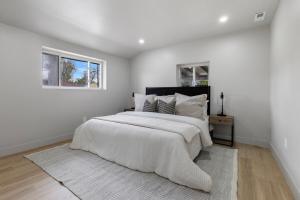 a white bedroom with a large bed and two windows at Centrally Located, Beautiful Park Hill Home in Denver
