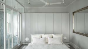 a white bedroom with a bed with white pillows at Kutti Beach House in Sydney +23 photos