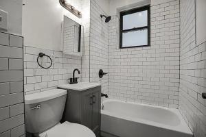 a bathroom with a toilet and a tub and a sink at The Marquee House in New York +14 photos