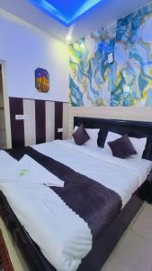 a bedroom with a large white bed with a painting on the wall at Hotel Mannat - Near Thyagaraj Sports Complex in New Delhi