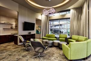 a lobby with green chairs and a flat screen tv at Hyatt House Seattle/Redmond in Redmond