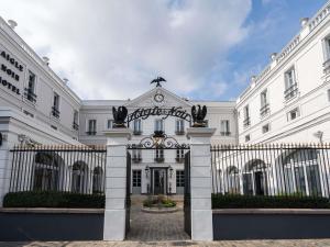 an entrance to a white building with a gate at Aigle Noir Hotel Fontainebleau - MGallery Collection in Fontainebleau