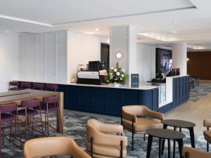 un vestíbulo con mesas, sillas y un mostrador en Mercure Brisbane Garden City, en Brisbane