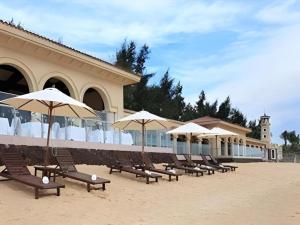 a row of chairs with umbrellas in front of a building at Hainan Yatai Hot Spring Hotel in Haikou