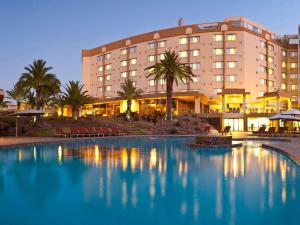 a hotel with a swimming pool in front of a building at Mövenpick Hotel Windhoek in Windhoek