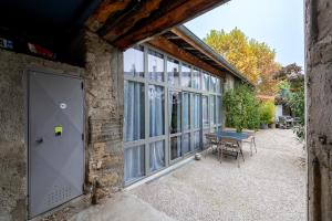 a stone building with a table and a large window at La grange moderne aux portes de Lyon in Vourles
