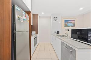 a kitchen with a stainless steel refrigerator and a sink at Spacious 3-Bedroom Apartment + Lifestyle Amenities in Downer
