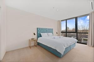 a white bedroom with a bed and a large window at Spacious 3-Bedroom Apartment + Lifestyle Amenities in Downer +15 photos