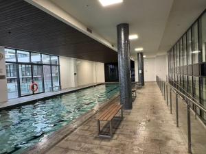 a large swimming pool with a bench in a building at Spacious 3-Bedroom Apartment + Lifestyle Amenities in Downer