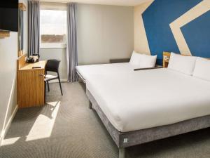 a hotel room with two beds and a desk at ibis budget London Heathrow Central in Hounslow +94 photos