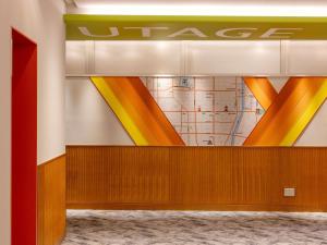 a wall with a mural of orange and yellow lines at ibis Styles Kyoto Shijo in Kyoto