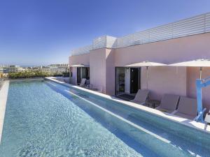 Una piscina con sillas y un edificio. en ibis Styles ST Pauls Bay Malta, en St Paul's Bay
