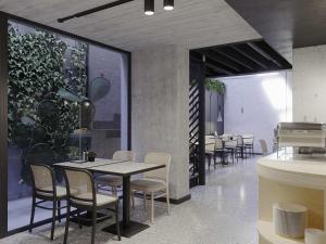 Un comedor con mesas y sillas y plantas. en ibis Styles ST Pauls Bay Malta, en St Paul's Bay