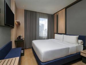 スラバヤにあるibis Surabaya Tidarの大きな白いベッドと窓のある寝室