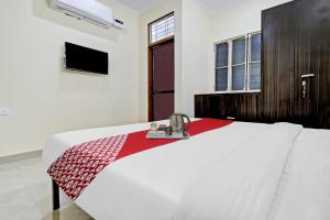 a bedroom with a white bed with a red blanket at Hotel O Green Apple in Jaipur