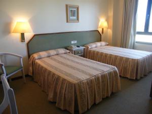 una habitación de hotel con 2 camas y una silla en Hotel Magallón, en Caspe