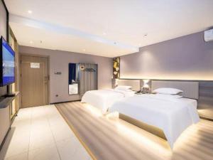 a bedroom with three beds and a flat screen tv at 7 Days Inn Luoyang Railway Station Wangcheng Avenue in Luoyang