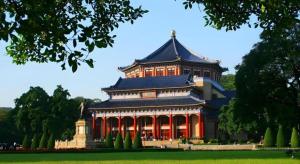a large building with red columns in a park at Kaiserdom Hotel Guangzhou Huangshidong Road Branch in Guangzhou